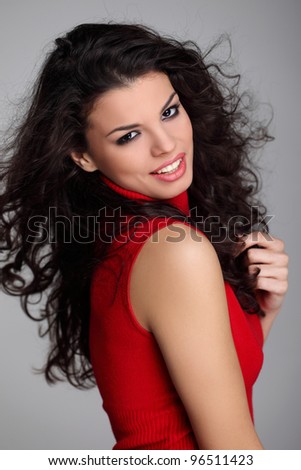 Attractive curly haired brunette girl in red turtleneck sweater smiling