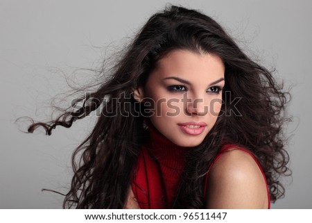 Pretty curly haired brunette girl in red turtleneck sweater smiling close up