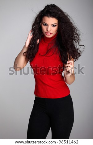 Attractive curly haired brunette girl in red turtleneck sweater and black tights posing sensually