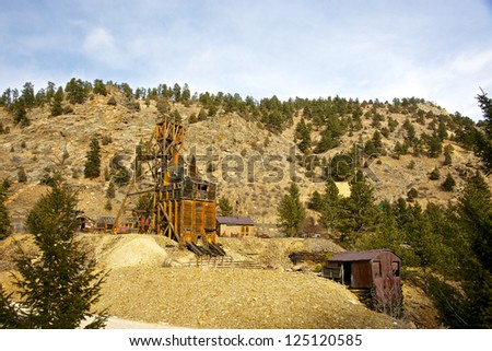 Rusting and beaten gold mine from the late 1800\'s stands in the western America wilderness.