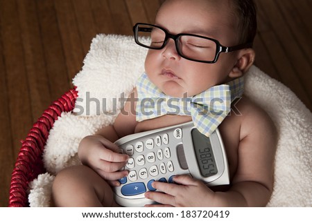 Little Accountant.  Adorable newborn wearing glasses and a bow-tie and holding a calculator.