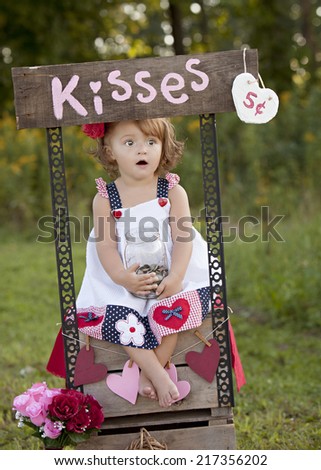 The Kissing Booth.  Adorable little girl sitting at a kissing booth.