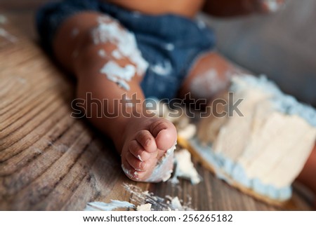Close-up of a baby's toes covered in vanilla cake icing.  Narrow depth of field with focus on the toes in front.