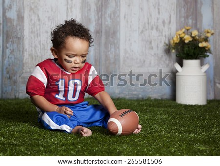 Football!  Adorable baby sitting in the grass wearing a football uniform.