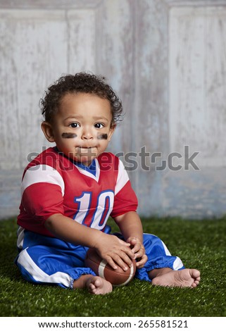 Football!  Adorable baby sitting in the grass wearing a football uniform.