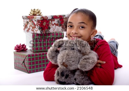 Adorable biracial girl hugging a stuffed animal and sitting next to a pile of wrapped Christmas presents.