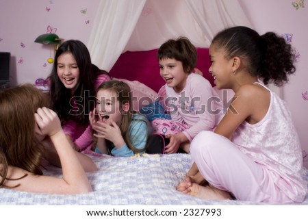 Five adorable girl friends talking and laughing at a slumber party.