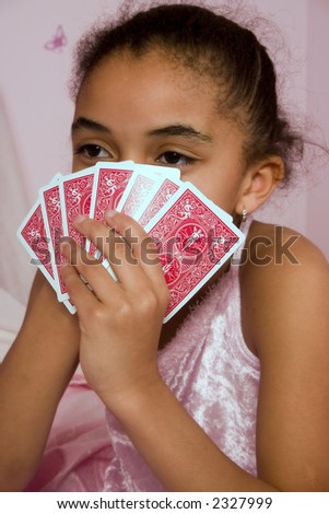 Adorable mulatto girl playing cards with her friends at a slumber party.