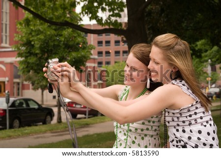 Two city teens smiling as they take self-portrait with a point-and-shoot camera.