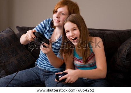 Two middle school girls at home playing an exciting video game together.