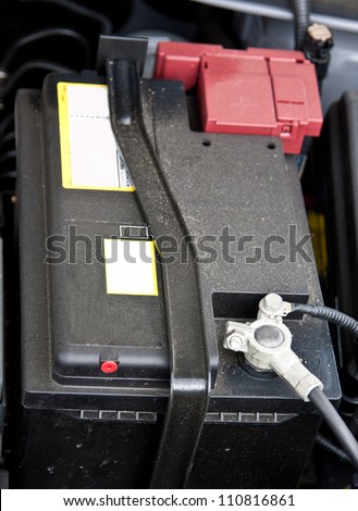 Accumulator (storage battery) under an open bonnet of a car