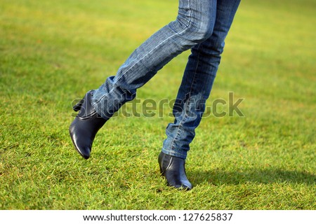 Legs of a young woman walking along the football ground