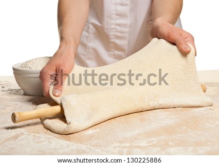 Hands rolling out dough in flour with rolling pin