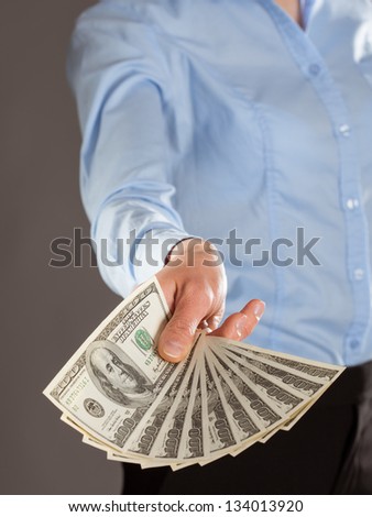 Woman\'s hand reaching out money on grey background