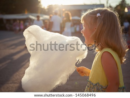 Charming little girl eating cotton candy