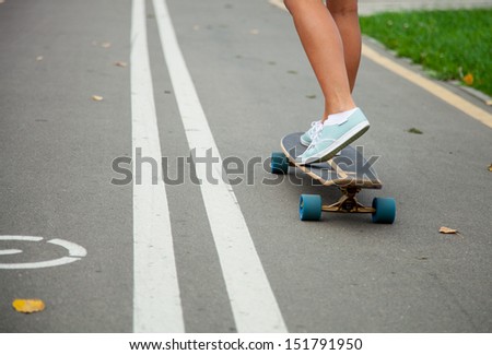 Unrecognizable girl skating on a longboard outdoors