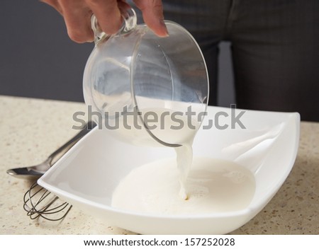 Housewife filling milk in a white bowl