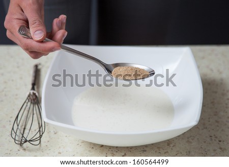 Unrecognizable housewife holding dry yeast in a spoon - closeup shot