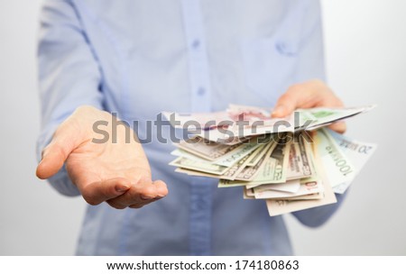 Unrecognizable woman reaching out empty hand and money on neutral background