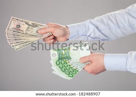 Businessman\'s hands reaching out dollar and euro banknotes