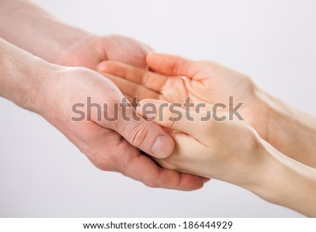 Two pairs of hands holding each other gently