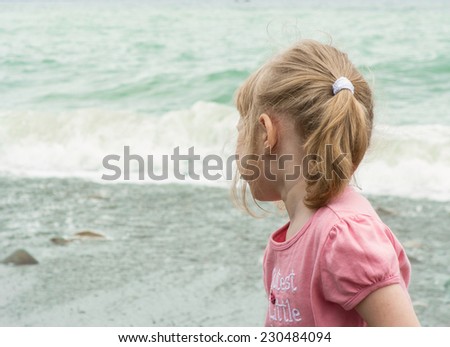 Little girl turning back to look at storming sea