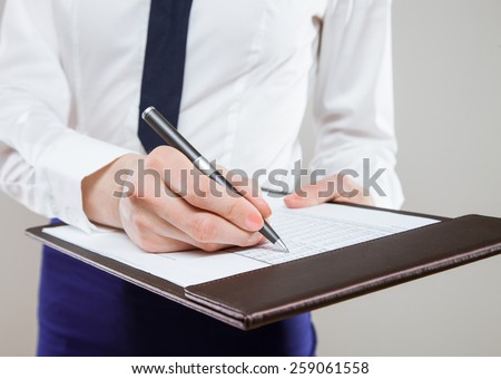 Unrecognizable young businesswoman  holding documents and a pen, neutral background