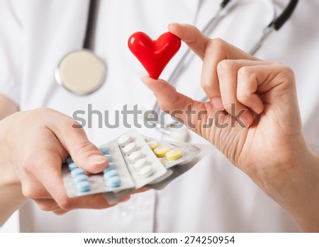 Doctor holding tablets and a red ceramic heart on white background