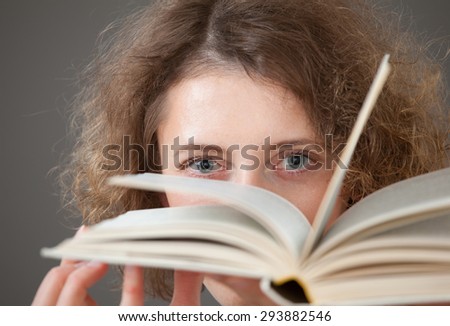 Portrait of a pretty young woman with a two books, gray background