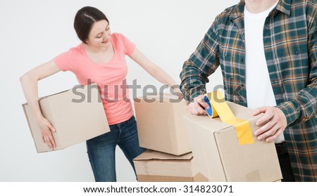 Young couple packing their things in cardboard boxes, neutral background
