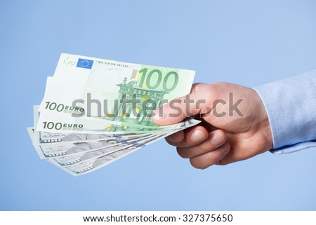 Businessman\'s hand reaching out euro banknotes, blue background