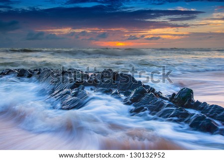 sun rise over the rocky coast with wave of sea