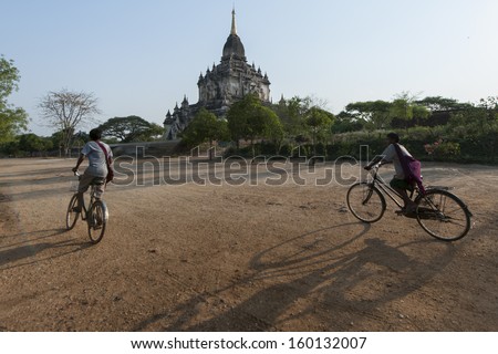 BAGAN, MYANMAR - FEB 14: Unidentified boys ride bike in front of pagoda on February 14, 2011 in Bagan Myanmar. average gap per capita is 1,612$ a year
