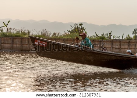 INLE LAKE, MYANMAR - FEBRUARY 15: Unidentified man riding a wooden boat in Inle Lake with its leg-rowing and fishing. Intha people is a major tourist destination on Feb 15, 2011 in Inle lake, Myanmar.