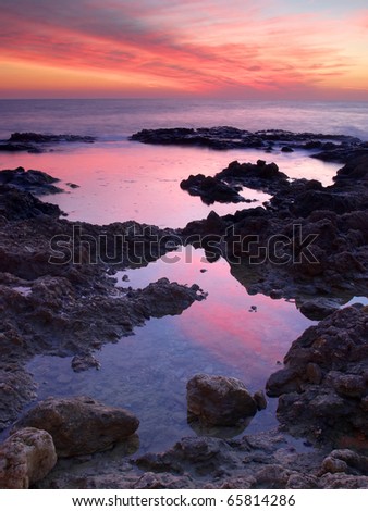 Reflection of the sundown in sea water amongst stone . Natural composition