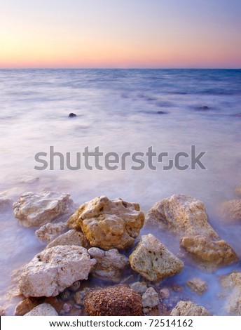 Seashore with stones during bright sundown. Natural composition