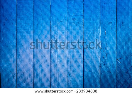 Blue painted wooden fence background with chain link fence shadow