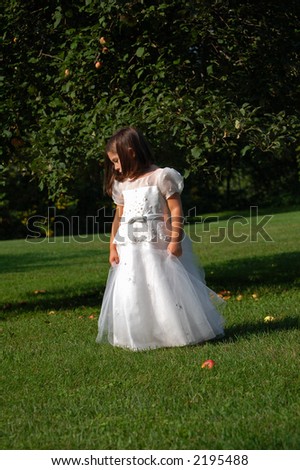 Four year old flower girl standing under an apple tree.