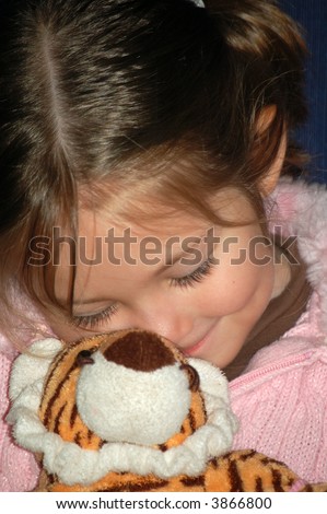 Four year old girl snuggling with her stuffed animal tiger.