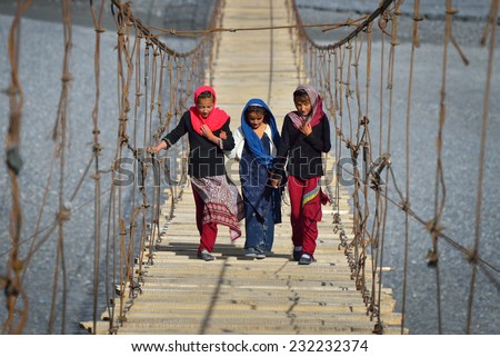 Passu, PAKISTAN - OCTOBER 24 : Unidentified Pakistani girls in Passu, Pakistan on 24 th October, 2014. The muslim girls cross the suspension bridge to come back to the home in the evening