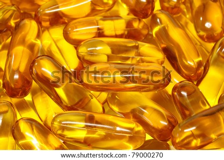 gold cod liver fish oil capsule, vitamin D on background.