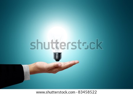 Light bulb in hand business woman on green background