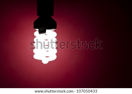 Energy saving light bulb glowing on red