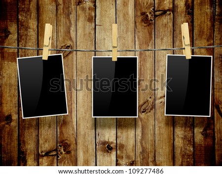 Photo frames with pins on rope over old aged wood background