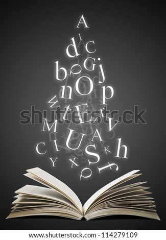 Open book with falling letters over black background