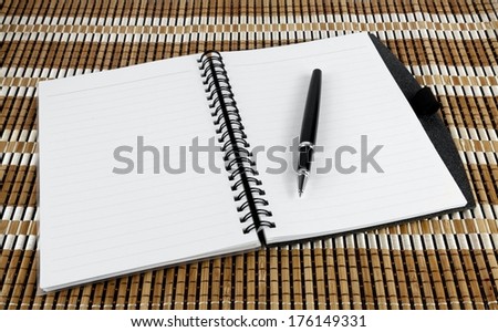 Open notebook with pen over textured bamboo mat