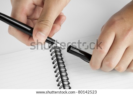 Hands removing the cap from the pen