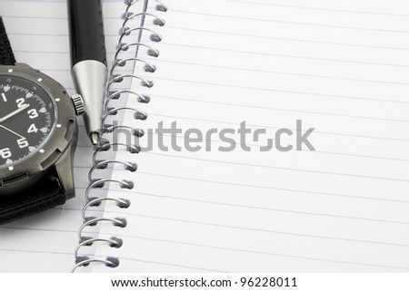 Pen and watch on notebook with room for text