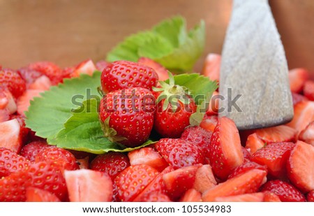 whole strawberries placed on strawberries leaves among sliced strawberries for jam