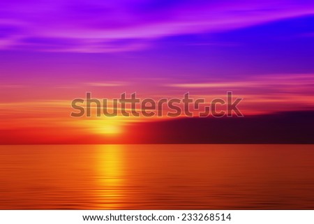 Burred sunset above the sea. Golden and red sea and purple sky.